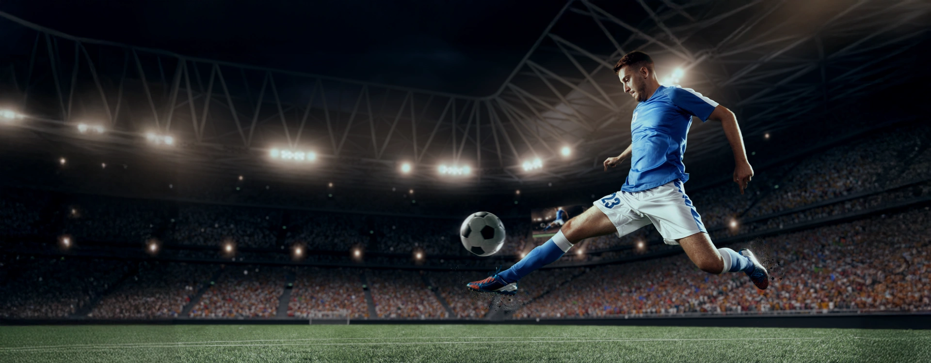 Footballer on the field, kicking the ball in a packed stadium